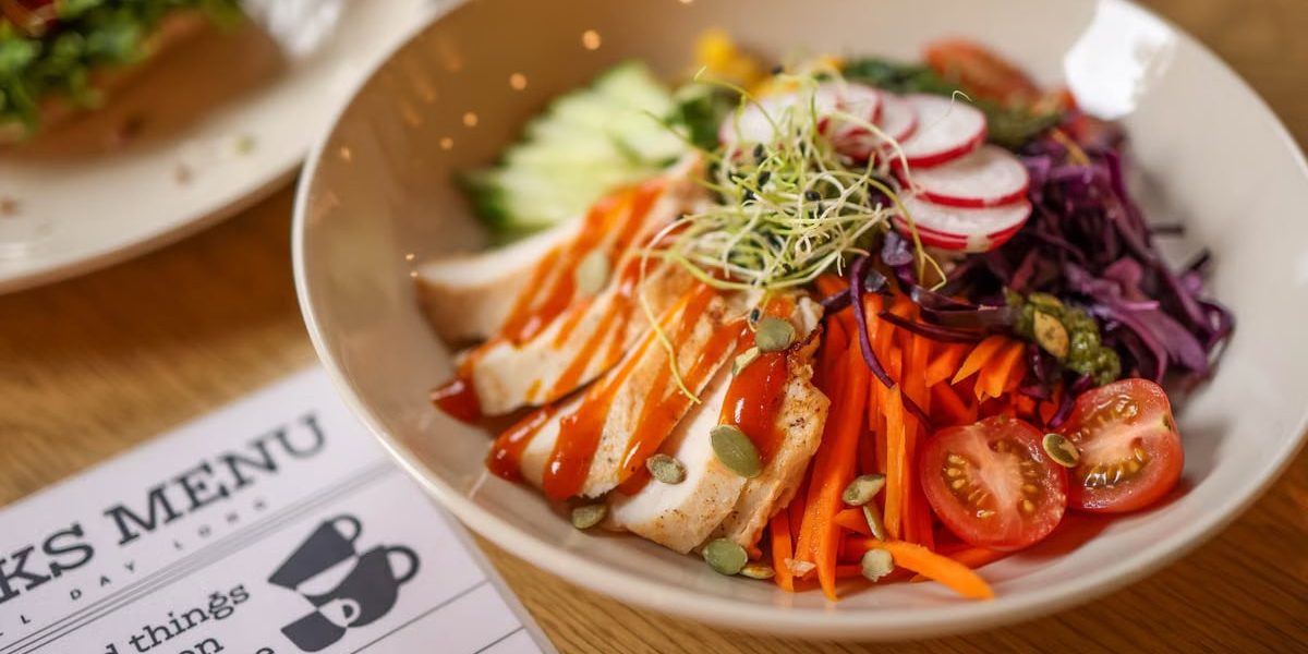 A vibrant salad bowl featuring fresh vegetables and grilled chicken on a wooden table.