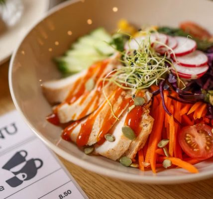 A vibrant salad bowl featuring fresh vegetables and grilled chicken on a wooden table.